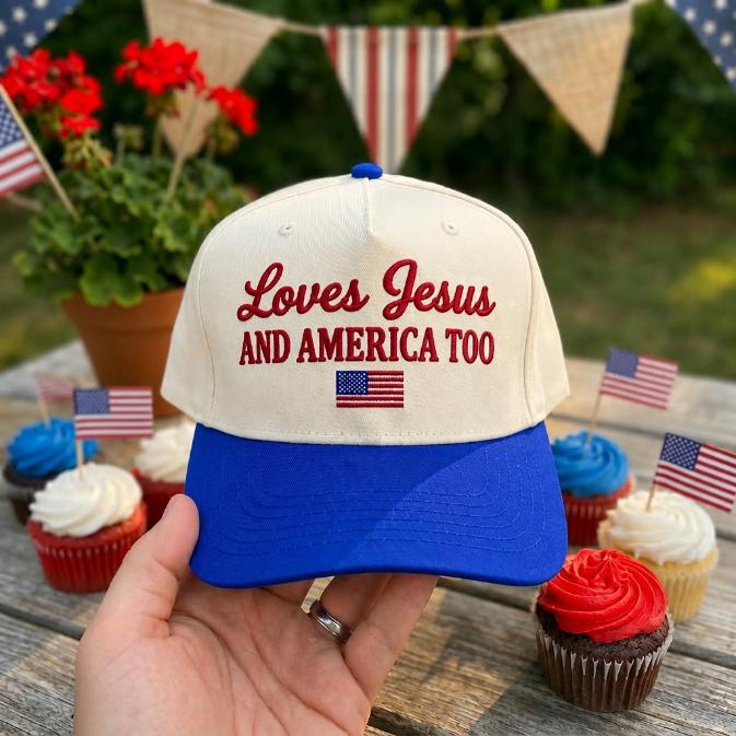 Front view of a cream and blue two-tone cap embroidered with “Loves Jesus and America Too” and a small American flag