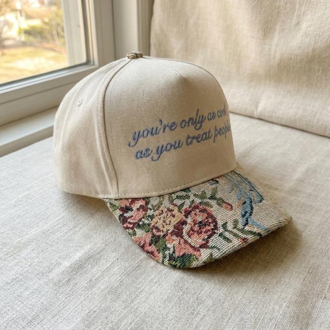 Angled view of khaki quote cap showing floral brim and blue embroidery