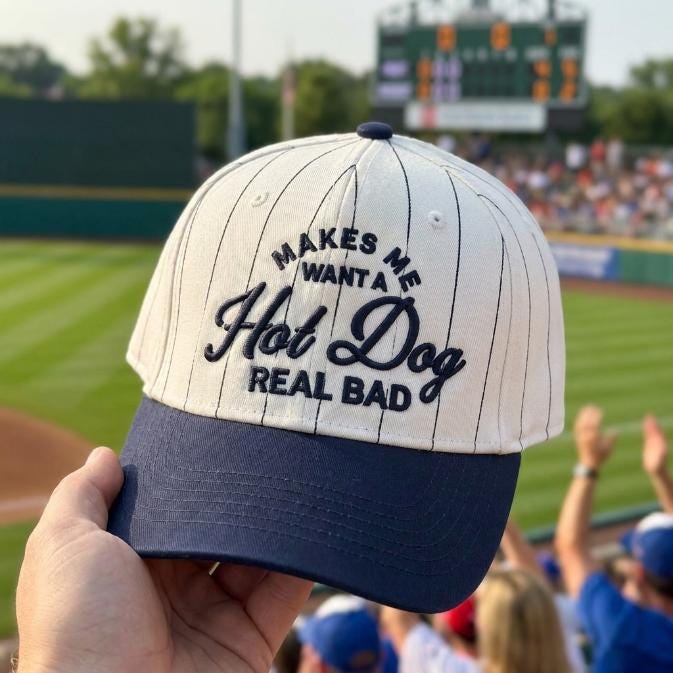 Pinstripe hat with “Makes Me Want a Hot Dog” embroidered front and navy brim