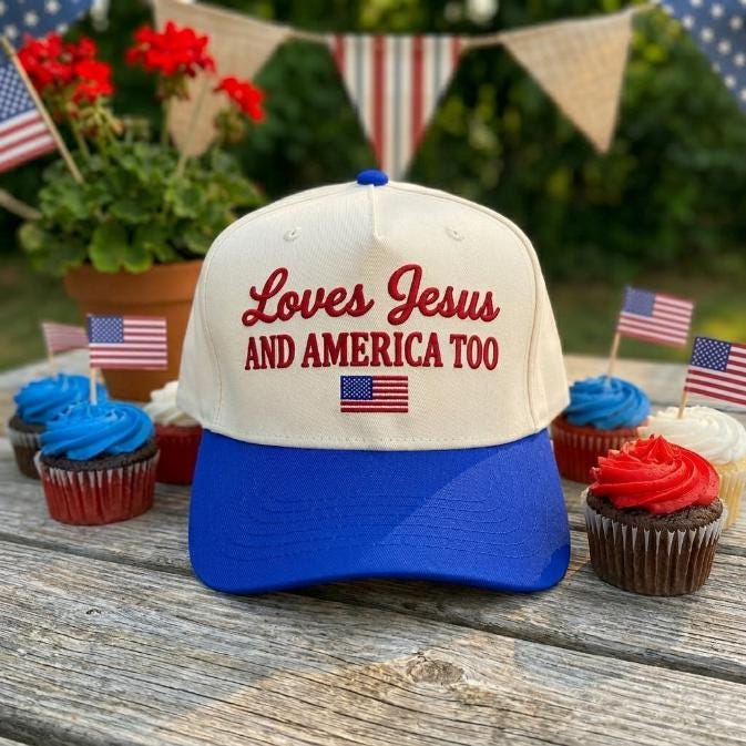 Standing front view of the cream and blue embroidered cap with Christian message and American flag