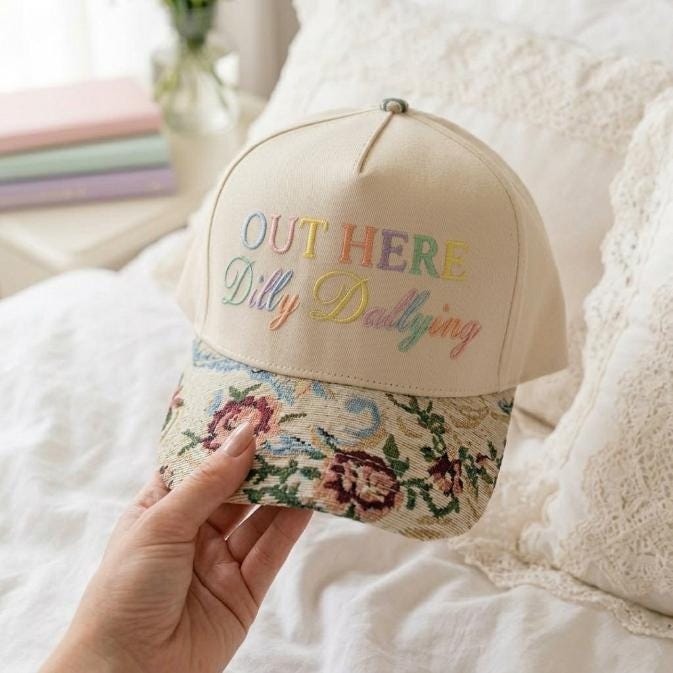 Angled view of cream embroidered hat with colorful floral curved brim