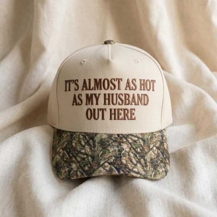 Embroidered husband joke hat displayed on light fabric with camouflage brim