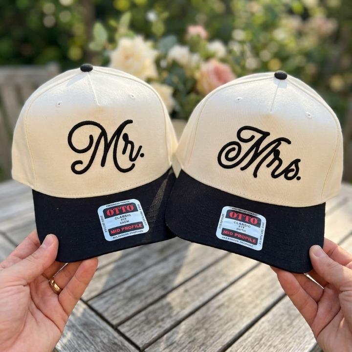 Matching cream and black Mr. and Mrs. embroidered hats displayed together