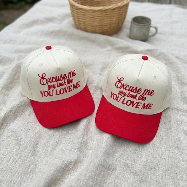 Pair of two-tone cream crown and red bill caps with playful front embroidery