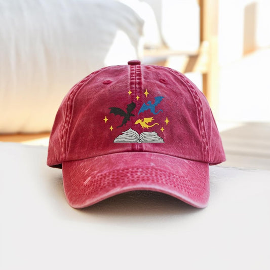 Red washed dad hat with embroidered dragons flying from an open book, fantasy style