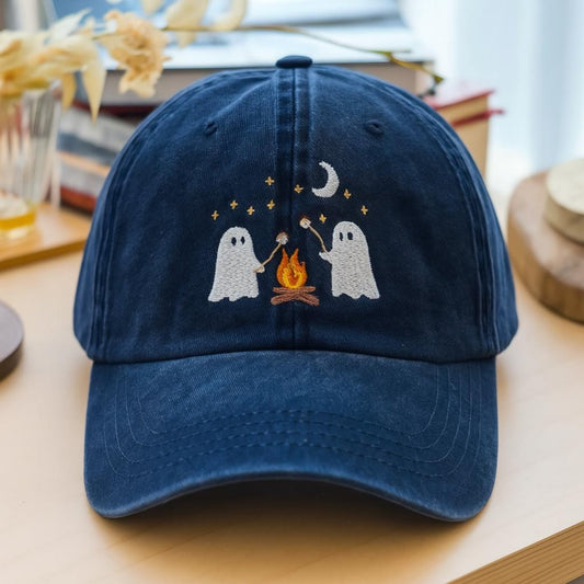 Navy washed dad hat with two embroidered ghosts roasting marshmallows over a fire beneath a moon – spooky and cute fall design