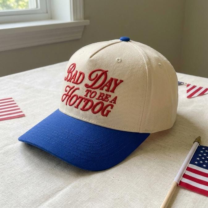 Angled view of the cream and blue cap showing its raised red lettering