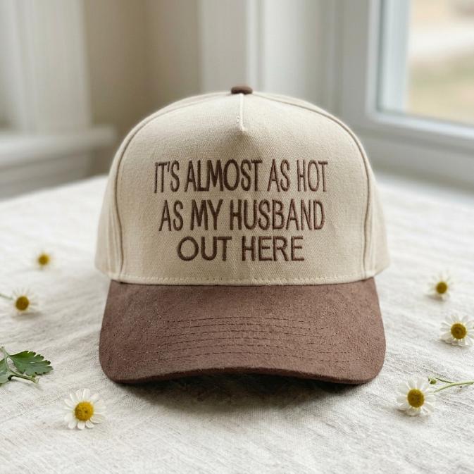 Two-tone trucker hat with the phrase It's Almost as Hot as My Husband Out Here on the front