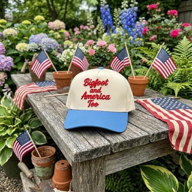 Bigfoot and America Too cap displayed on a rustic table in an American-themed garden setting