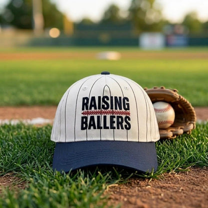 Raising Ballers baseball hat resting on grass beside a baseball glove