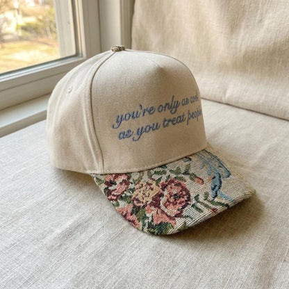 Angled view of khaki quote cap showing floral brim and blue embroidery