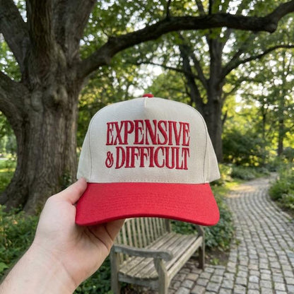 Two-tone cream and red trucker hat embroidered with “Expensive & Difficult” lettering