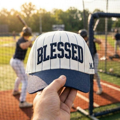 Blessed pinstripe baseball hat held at a baseball practice field