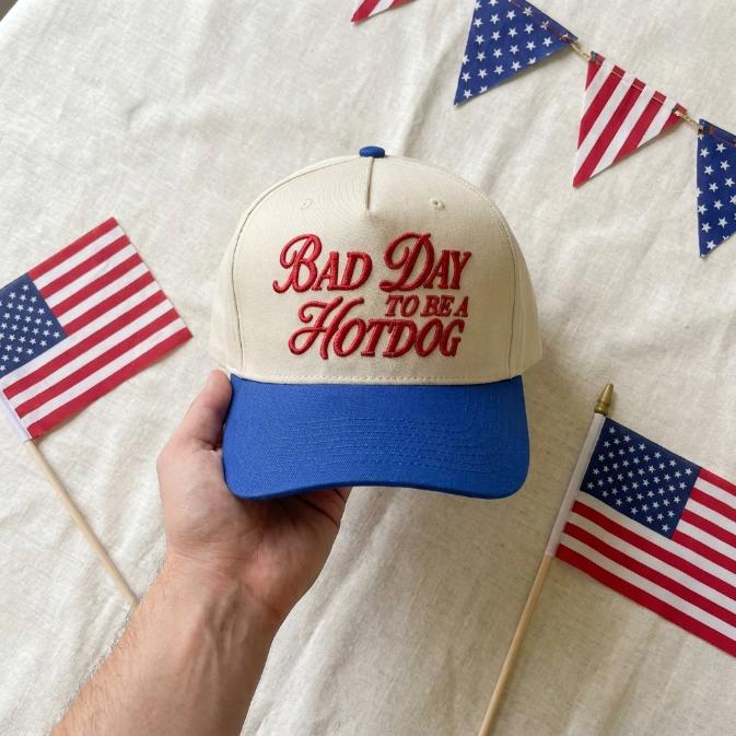 Two-tone embroidered hotdog cap held against patriotic table decorations