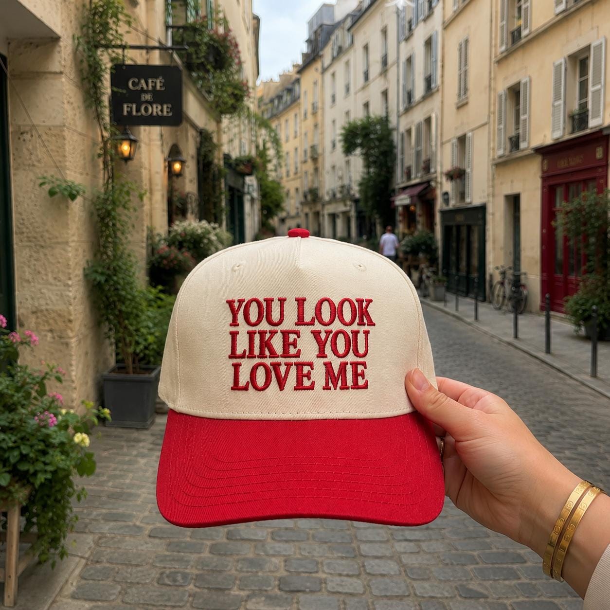 Embroidered romantic trucker cap held on a cobblestone street