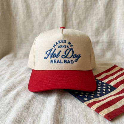 Cream and red hot dog embroidered trucker hat displayed with an American flag