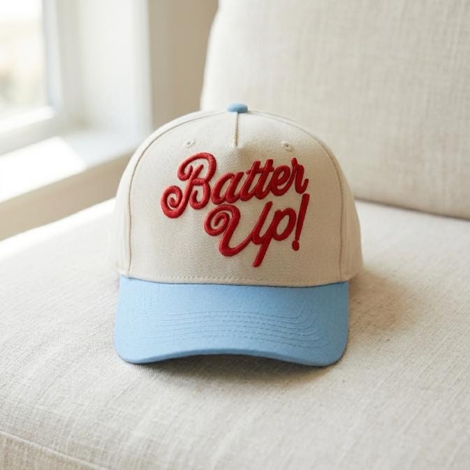 Front view of cream and light blue trucker cap with red “Bater Up!” embroidery