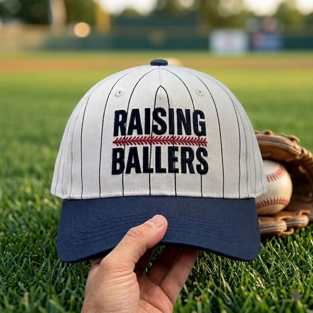 Raising Ballers pinstripe hat displayed on a baseball field with glove and ball