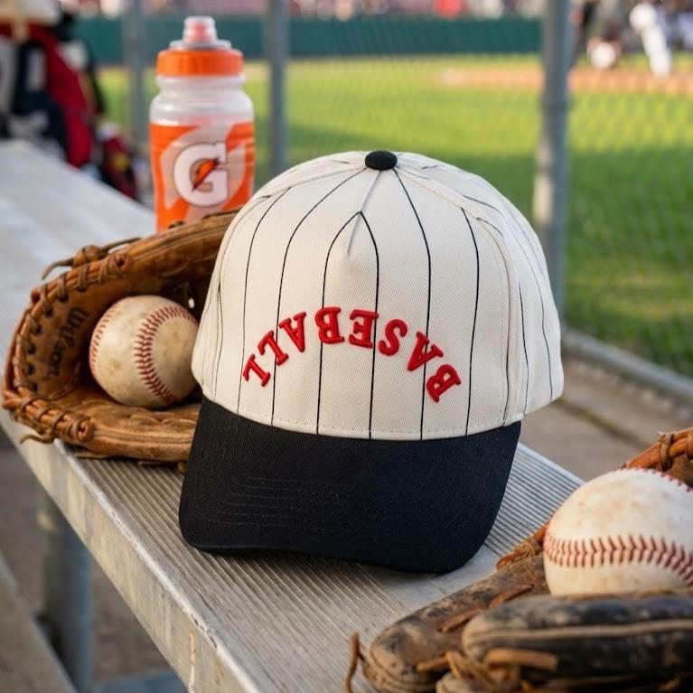 Baseball pinstripe hat displayed beside gloves and baseballs at a ballpark