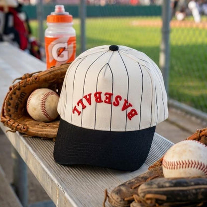 Baseball pinstripe hat displayed beside gloves and baseballs at a ballpark