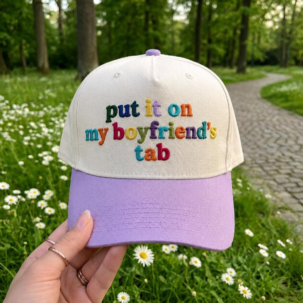 Embroidered boyfriend tab hat shown outdoors on a garden path