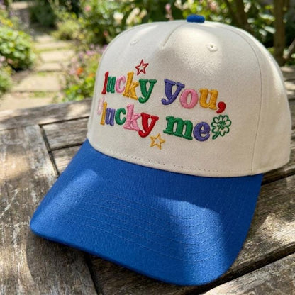 Close-up of colorful Lucky You Lucky Me embroidery with star and clover details on a cream hat