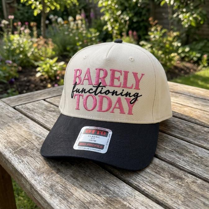 Angled view of Barely Functioning Today embroidered trucker hat on a wooden table
