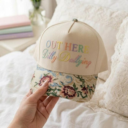 Angled view of cream embroidered hat with colorful floral curved brim