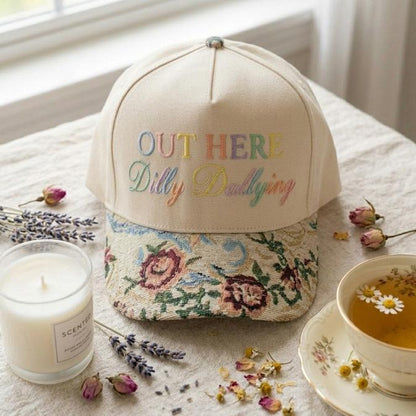 Front view of floral embroidered hat styled beside a candle and tea
