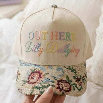 Cream floral embroidered hat with “OUT HERE Dilly Dallying” lettering and botanical brim