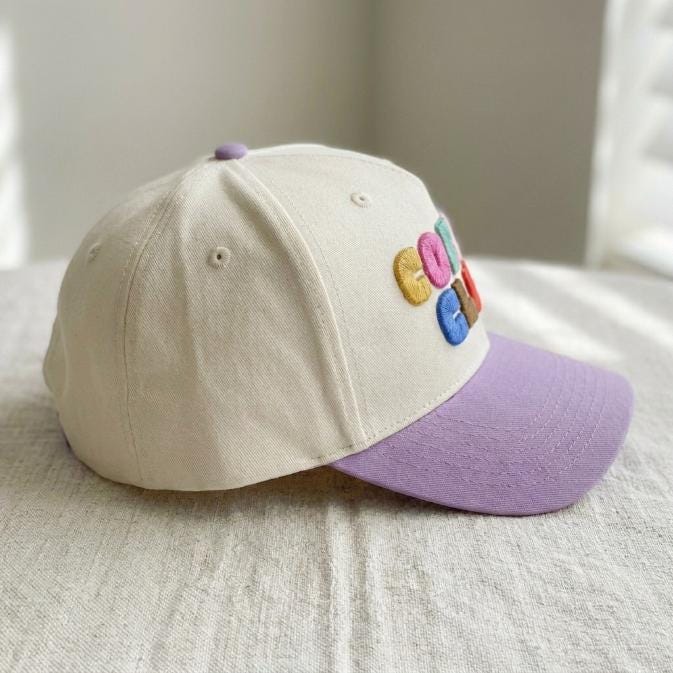 Side view showing the cream crown and lavender curved brim of the Coffee Club hat