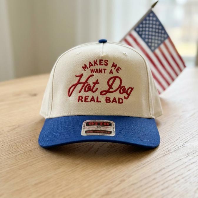 Front view of embroidered hot dog trucker hat on a wooden table