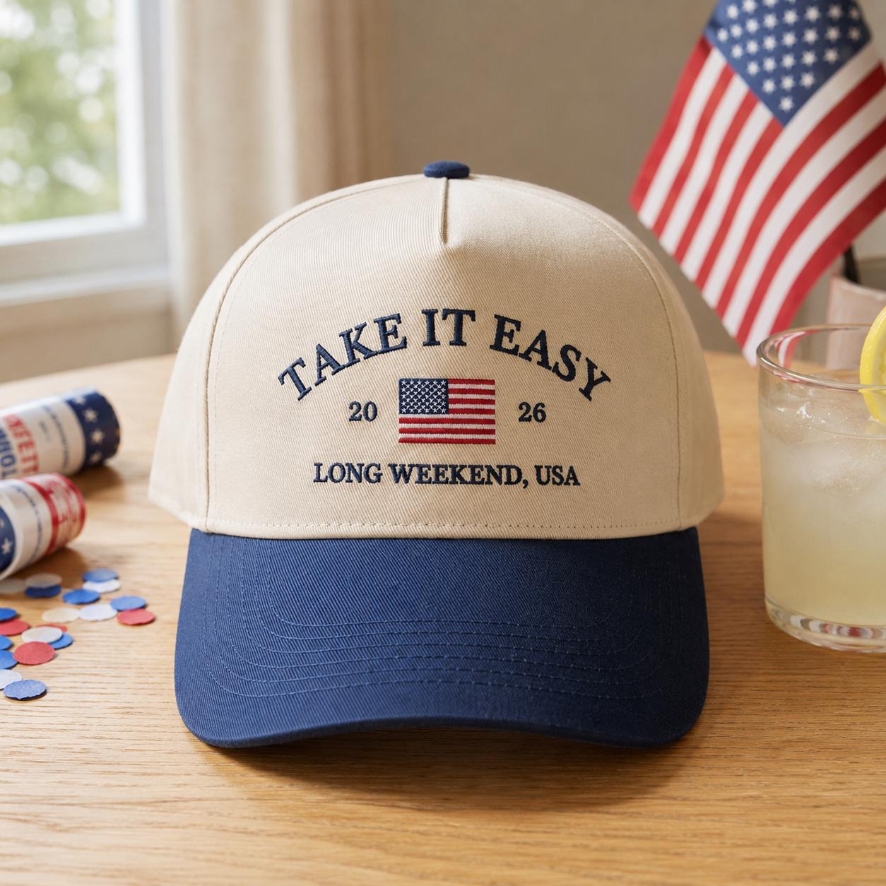 Front view of a cream and navy two-tone trucker hat embroidered with Take It Easy, an American flag, and Long Weekend USA