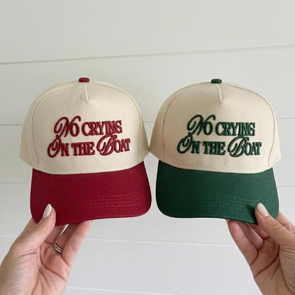 Two-tone embroidered trucker hats reading No Crying On The Boat in burgundy and forest green
