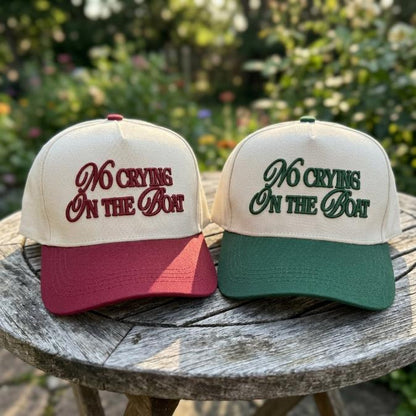 Close view of No Crying On The Boat embroidered two-tone hats on an outdoor table