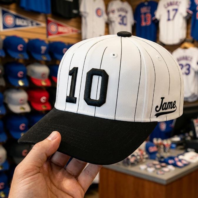 Close-up of white pinstripe baseball hat with black bill, number 10, and script side detail