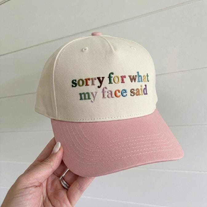 Two-tone cream and pink embroidered trucker hat reading sorry for what my face said