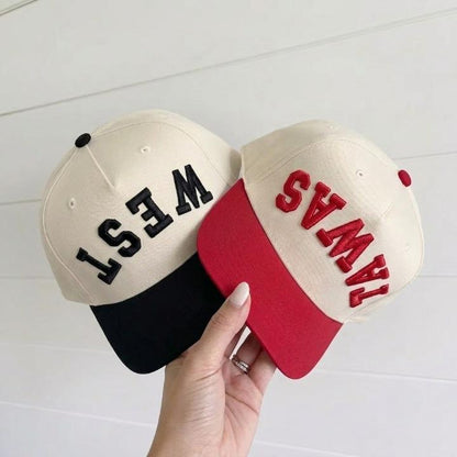 Two two-tone trucker caps with embroidered WEST and EAST lettering in black and red