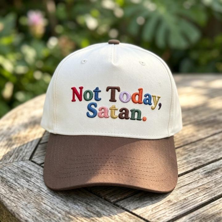 Close-up of “Not Today, Satan.” embroidered trucker cap on a wooden table