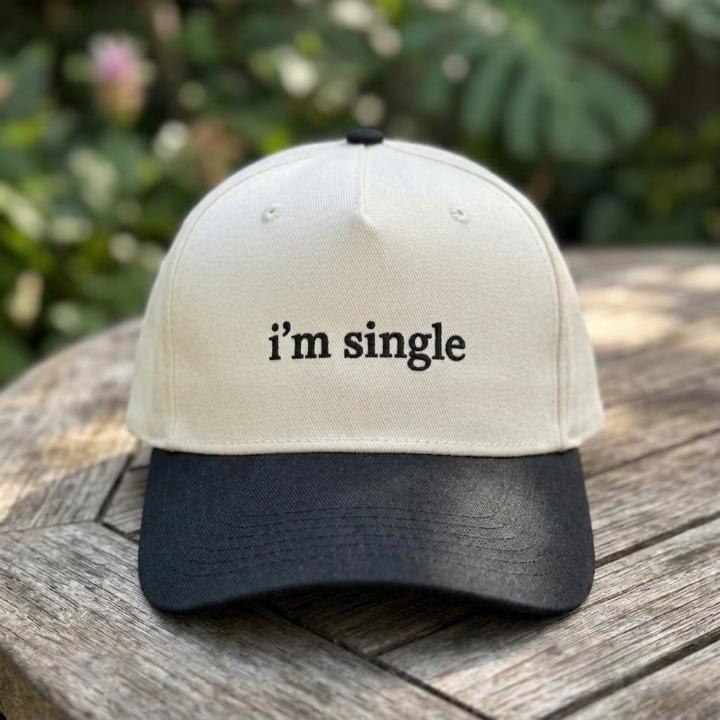 Front view of an “i’m single” embroidered two-tone trucker hat outdoors