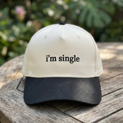 Front view of an “i’m single” embroidered two-tone trucker hat outdoors