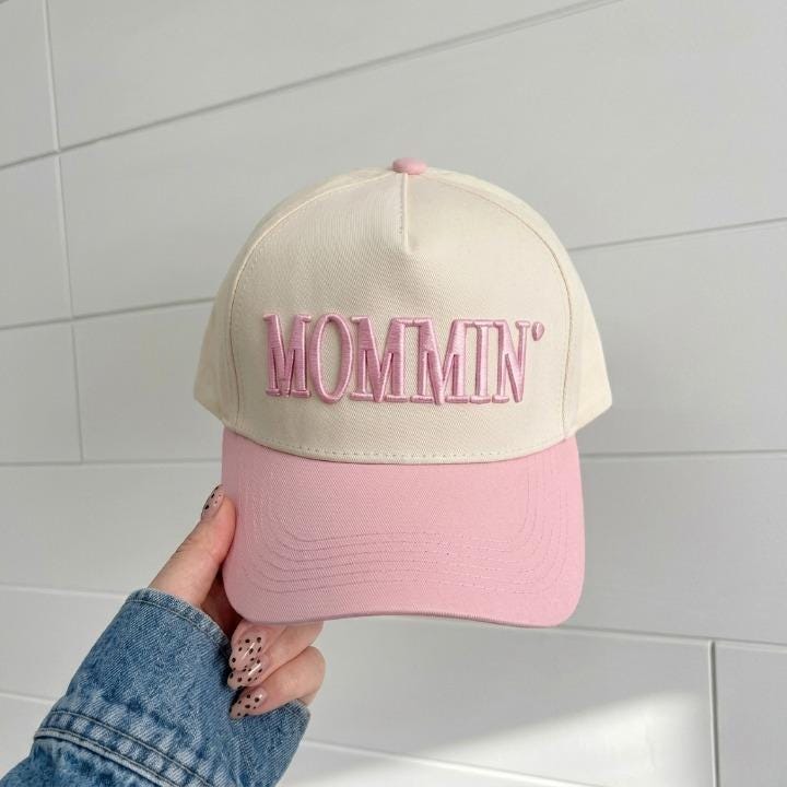 Front view of a cream and pink MOMMIN embroidered trucker hat