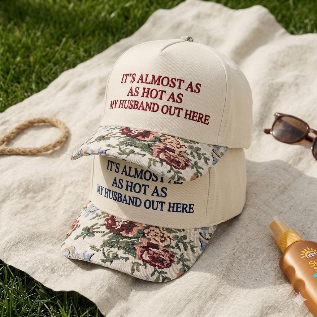 Embroidered floral brim hat displayed on a blanket with sunglasses and sunscreen