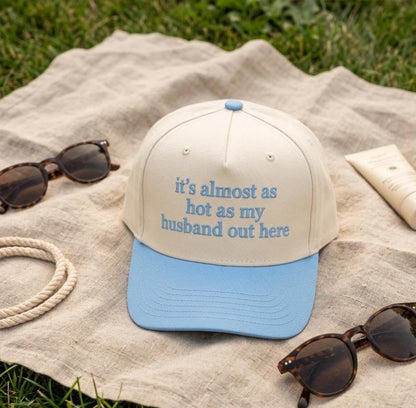 Cream trucker hat with blue brim displayed on a picnic blanket
