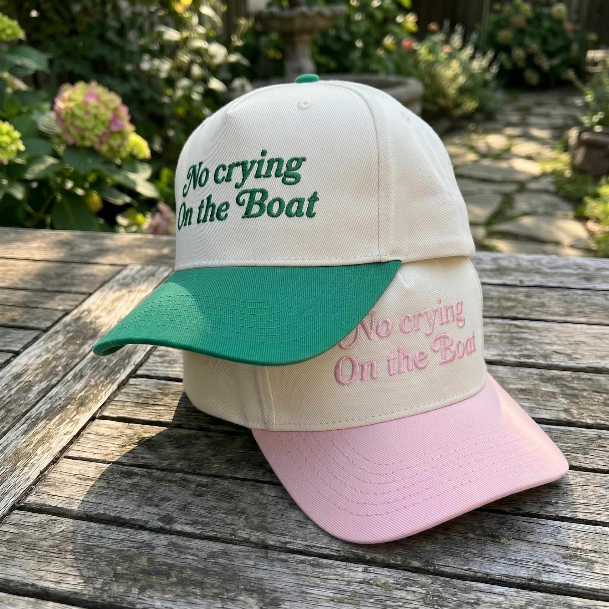 Cream and pink two-tone trucker hat embroidered with “No Crying On the Boat”
