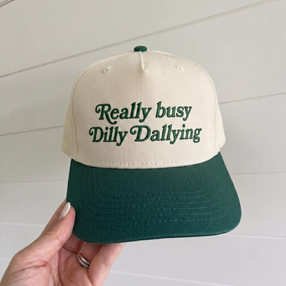 Cream and forest green two-tone trucker hat with Really Busy Dilly Dallying embroidered text