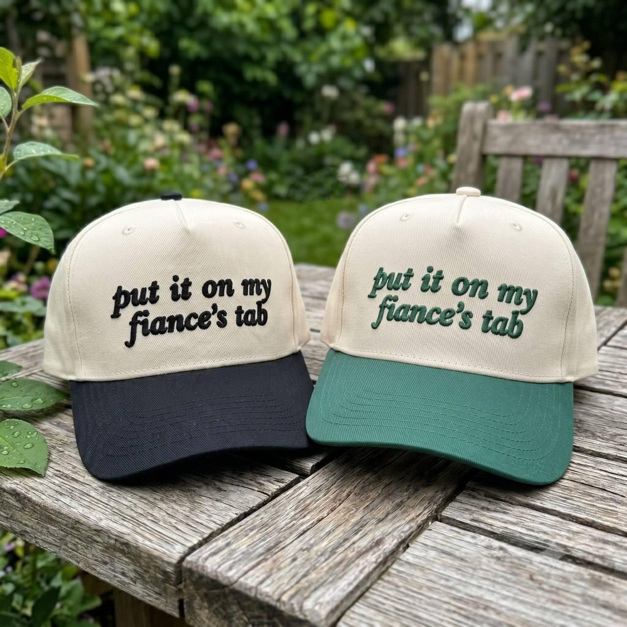 Black brim embroidered fiance's tab trucker hat held outdoors