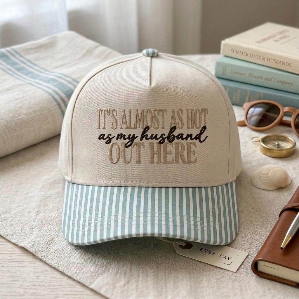 Cream embroidered quote hat with light blue striped brim styled on a bed