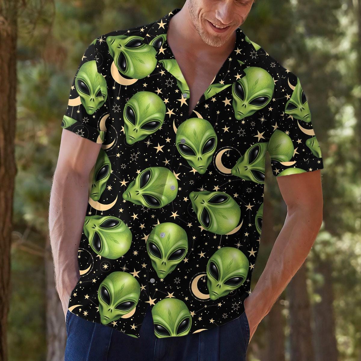 Model wearing a green alien face Hawaiian shirt in a casual outdoor setting