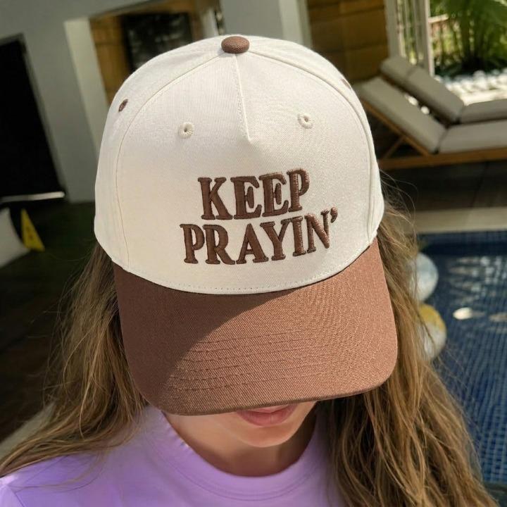 Person wearing a cream and brown embroidered prayer hat outdoors